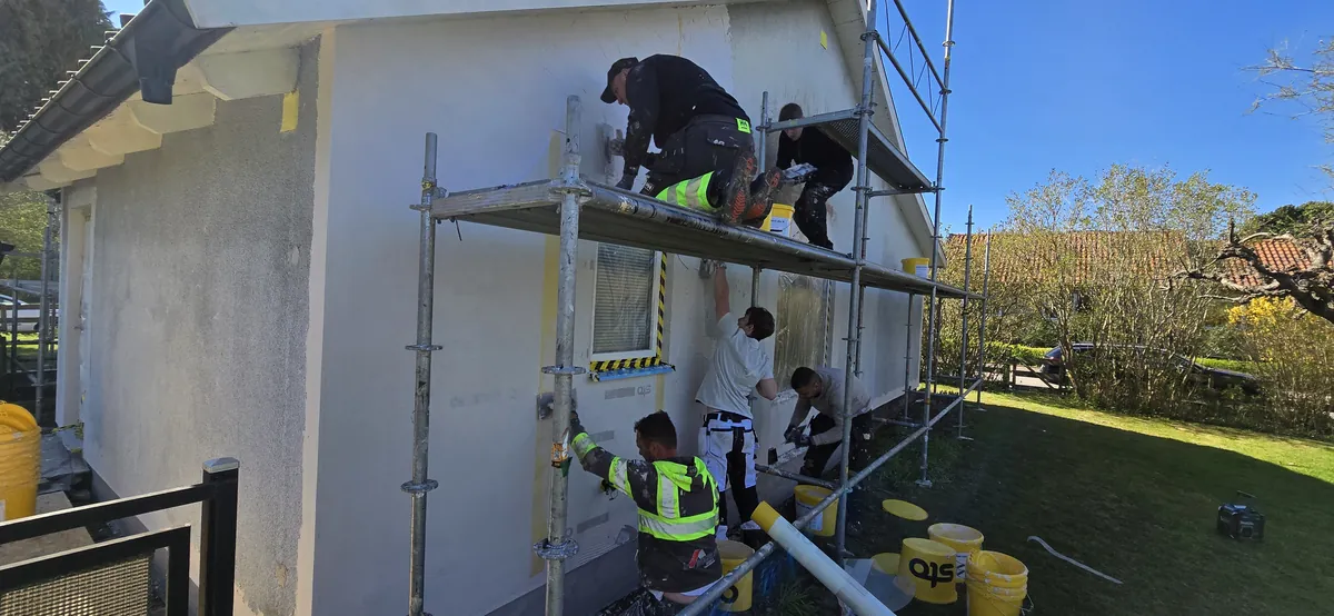 Arbete från byggnadsställning vid en ljus putsfasad i Ängelholm.