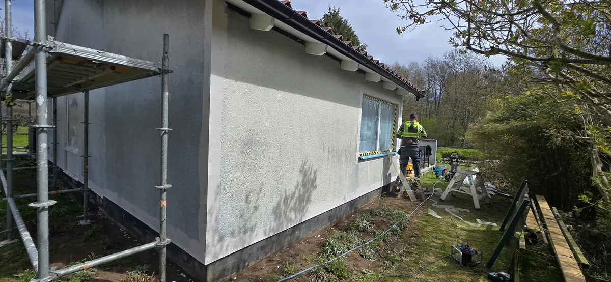 Rendered façade and scaffolding along a detached house in Ängelholm.