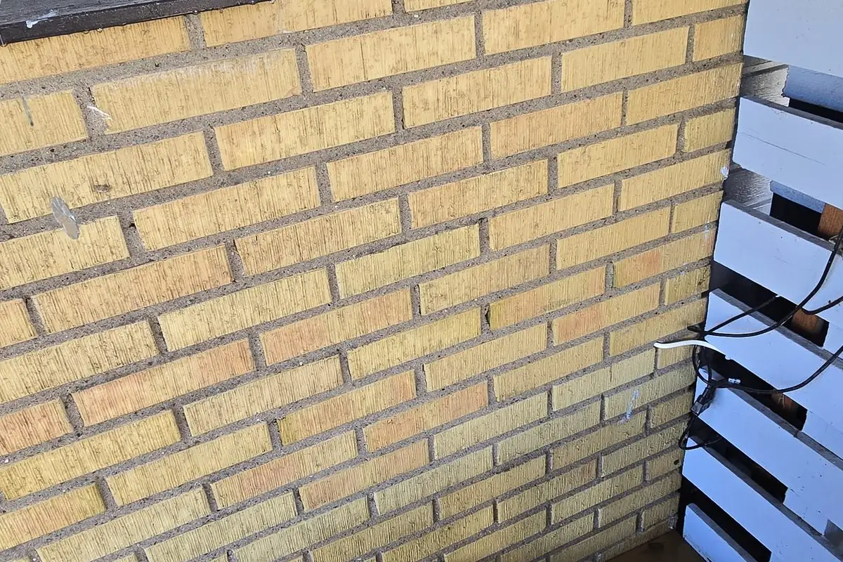 Närbild av gul tegelfasad med fogar och täckta ytor i Åkarp.