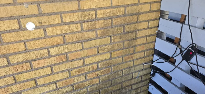 Yellow brick wall beside covered windows and work materials in Åkarp.