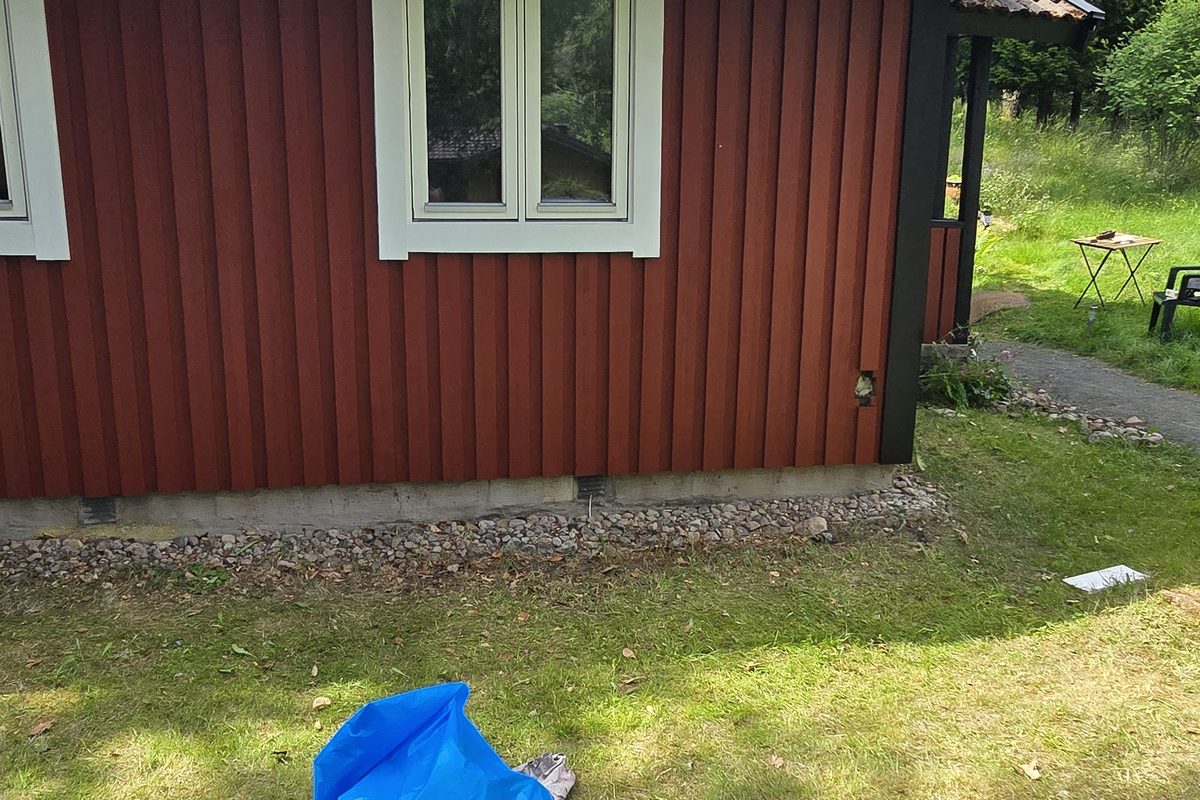 Rödmålad träpanel med vitmålat fönsterfoder och svart takfot på byggnaden i Lycke