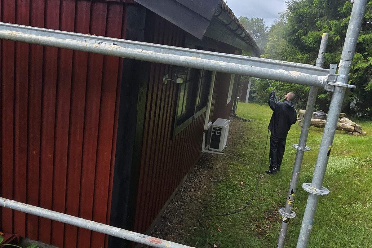Byggnadsställning sedd underifrån längs den rödmålade träpanelen i Lycke