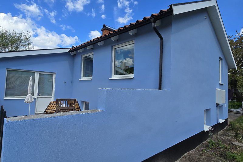 Ljusblå putsfasad på villa i Ängelholm efter fasadmålning av NLL Måleri